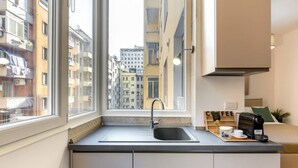 Eine kleine Küche mit Fenster, Spüle und Kaffeemaschine auf der Arbeitsfläche.