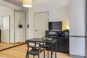 Una cocina moderna con una mesa de comedor, sillas, televisor y refrigerador.