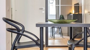 Ein moderner Essbereich mit Tisch und Stühlen, eine grüne Schüssel mit einem Kaktus und Blick in einen anderen Raum.