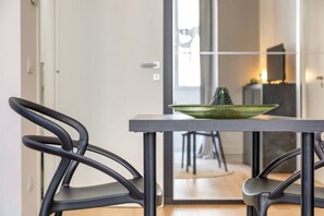 A modern dining area with a table and chairs, a green bowl with a cactus, and a view into another room.