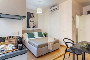 A modern bedroom with a bed, bedside table, and a dining area with a chair. - Easylife - Cozy studio close to the center (Milano)