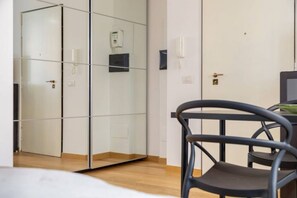 A room with a mirrored wardrobe, a desk with a chair, and a bedside table. - Easylife - Cozy studio close to the center (Milano)