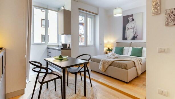 Eine moderne Wohnung mit Essbereich, Küchenzeile und einem Schlafzimmer mit Bett und Kissen.