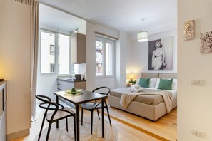Un apartamento moderno con comedor, kitchenette y un dormitorio con cama y almohadas.