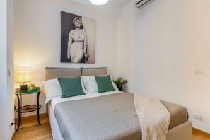 Un dormitorio con una cama, una mesita de noche, una lámpara y un cuadro colgado en la pared.