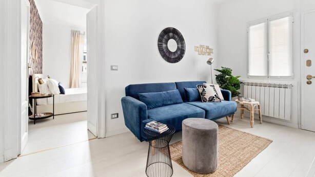 A modern living room with a blue sofa, a round rug, and a small round table. - Easylife - Golden Navy Design apt Pta Venezia (Milano)
