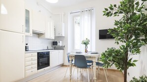 A modern kitchen with white cabinets, a microwave, and a dining area with a table and chairs. - Easylife - Comfortable three-room apartment in the heart of Milan (Milano)