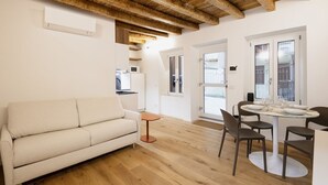Un salon moderne avec un plafond en bois, un canapé blanc, une table à manger avec des chaises et une petite table d’appoint.