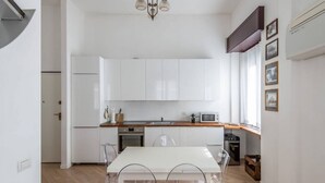 A modern kitchen with white cabinets, a wooden countertop, and a dining area with a white table and chairs.