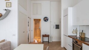 A narrow kitchen with white cabinets, a wooden countertop, and a built-in oven.