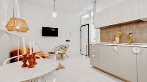 Una cocina moderna con armarios blancos, una mesa de comedor redonda y una lámpara colgante de mimbre.