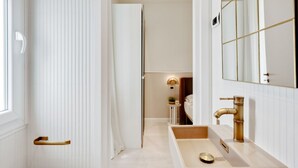 Un baño moderno con un espejo grande, un grifo dorado y un tocador blanco.
