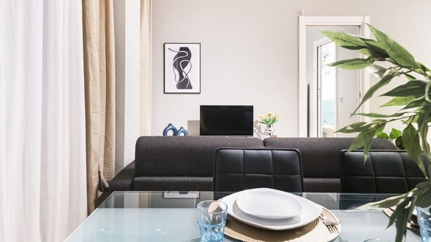 Een moderne eetruimte met een glazen tafel, zwarte stoelen met bekleding en een minimalistische inrichting.
