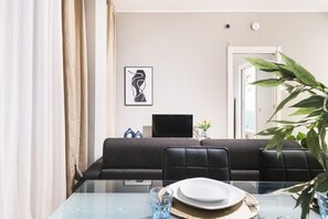 Un espace repas moderne avec une table en verre, des chaises à revêtement noir et un décor minimaliste.