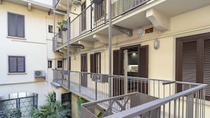 Un immeuble résidentiel à plusieurs étages, doté de balcons, de climatiseurs et d’une entrée sécurisée par un portail.