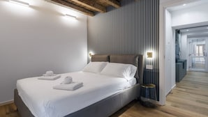 Une chambre à coucher moderne avec un lit, du linge de lit blanc et une tête de lit en bois.