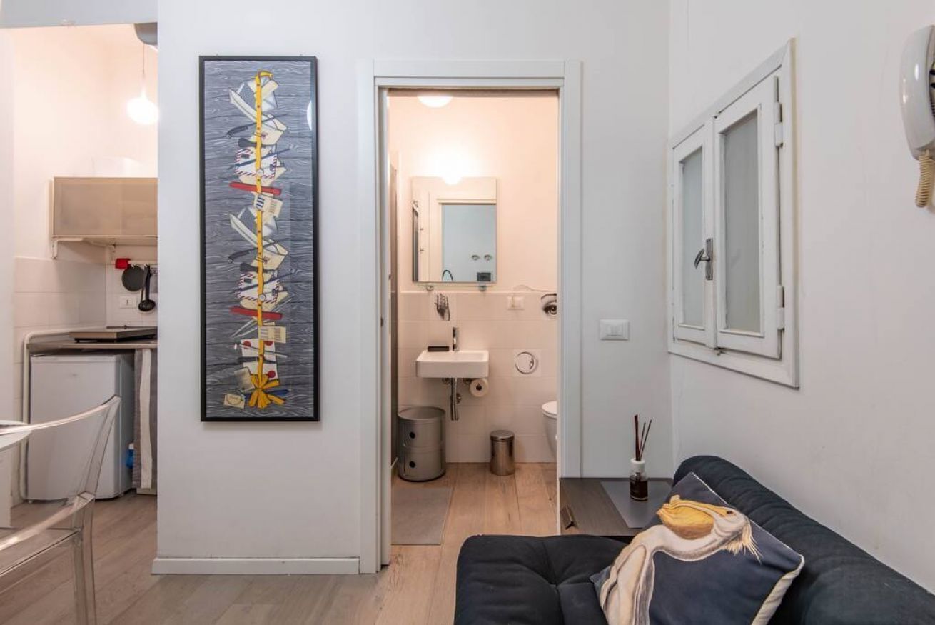 Una sala de estar moderna con un sofá negro y un cuadro en la pared.