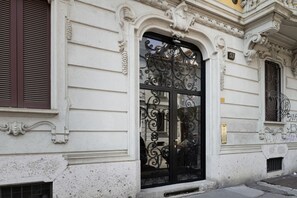 En byggnadsfasad med utsmyckade arkitektoniska detaljer, inklusive en stor, svart smidesjärnsport och dekorativa lister.