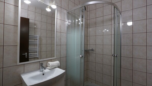 Un baño moderno con cabina de ducha de vidrio, un lavabo blanco y un espejo sobre el lavabo.