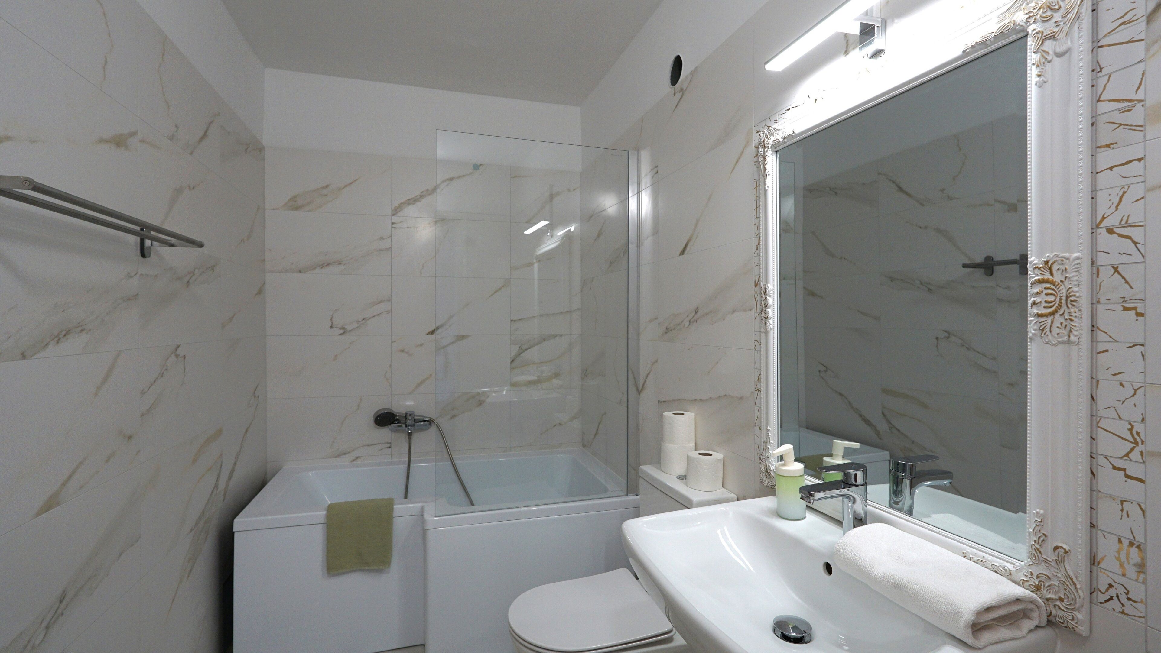 A bathroom with a shower, toilet, sink, and mirror.
