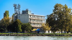 Un edificio frente al agua con balcón, asta de bandera y toldo azul.