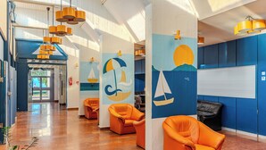 Un vestíbulo amplio con asientos color naranja, murales náuticos y un interior luminoso y bien iluminado.