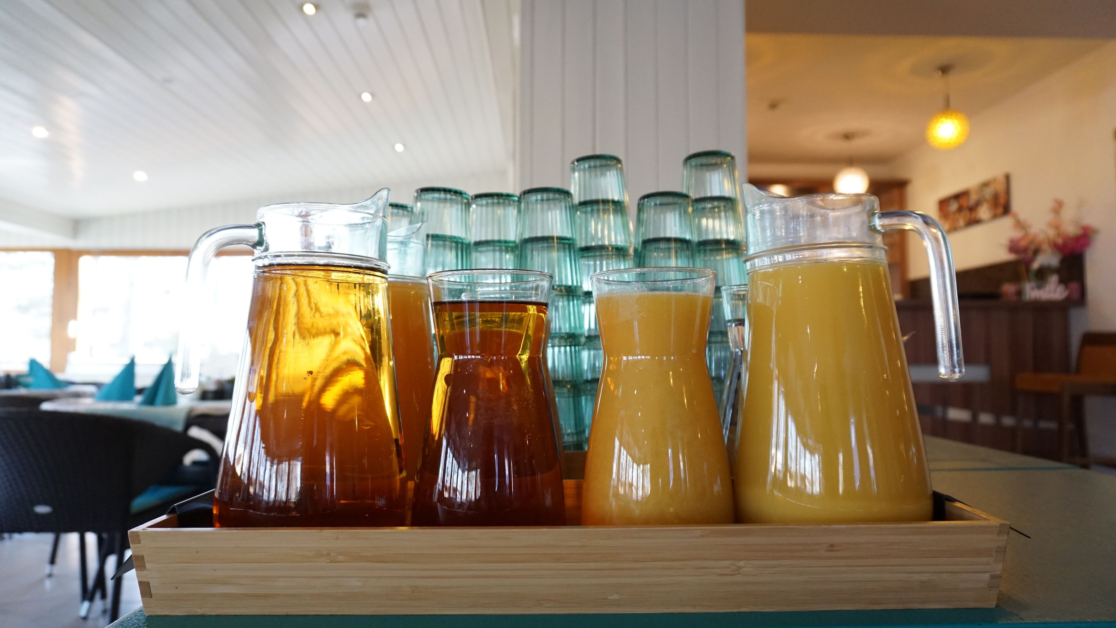 Una bandeja de madera con cuatro jarras de bebidas.