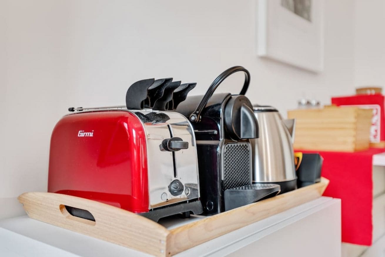 Eine Küchenarbeitsplatte mit einem roten Toaster, einem Wasserkocher und einer Kaffeemaschine.