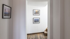 A hallway with a wooden floor and two framed pictures on the wall. - Easylife - Double Suite (Milano)