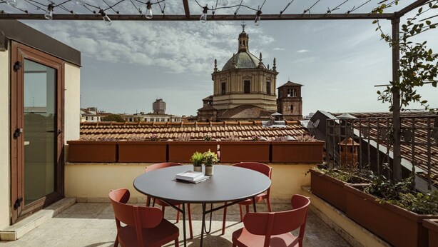 A rooftop terrace with a round table and red chairs, overlooking a historic building with a dome. - Easylife - Double Suite (Milano)