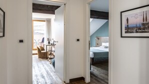 A hotel room with a bed, a desk, and a chair. There is a window with curtains and a view of the outside. - Easylife - Double Suite (Milano)