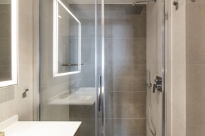 A modern bathroom with a glass shower enclosure, a white sink, and a mirror. - Easylife  - Exclusive refuge in the Duomo area (Milano)