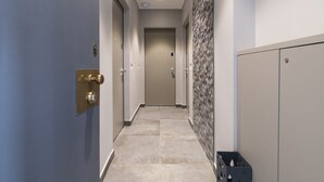 Un couloir avec une porte bleue, un casier en métal et un mur orné de motifs.