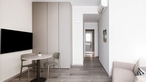 Un salon moderne avec une table à manger ronde, un canapé et un téléviseur fixé au mur.