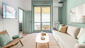 A living room with a sofa, a coffee table, a wicker chair, and a television. - Easylife - Warm gem in Porta Venezia (Milano)