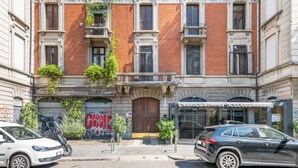 A building with a red brick facade, multiple windows, and a central entrance with a wooden door. - Easylife - Warm gem in Porta Venezia (Milano)