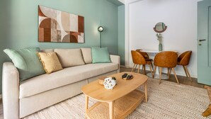 A living room with a sofa, coffee table, and a dining area with chairs and a table. - Easylife - Warm gem in Porta Venezia (Milano)