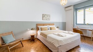 A bedroom with a bed, a desk, a chair, a lamp, and a hanging light fixture. - Easylife - Warm gem in Porta Venezia (Milano)