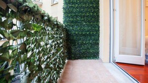 Ein Gang mit einer grünen Hecke als Wand und einem Fliesenboden.