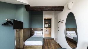 A hotel room with a wooden floor, a large mirror, a bed, a TV, and a hanging coat rack. - Easylife - Single Suite with view (Milano)