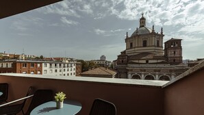 A balcony with a table and chairs, overlooking a historic building with a dome and bell tower. - Easylife - Single Suite with view (Milano)