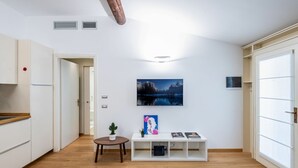 A modern kitchen with white cabinets, a wooden countertop, and a dining area with a small table and chairs. - Easylife - Romantic flat in Darsena (Navigli) (Milano)