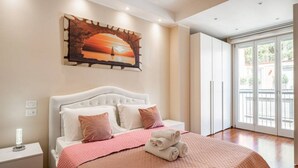 Quarto com cama, travesseiros, mesa de cabeceira, um quadro e vista através de uma porta de vidro.