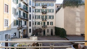 Un edificio de varios pisos con balcones, un patio interior y vistas a la calle.
