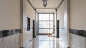 Un pasillo con paredes de mármol y piso pulido, que conduce a un ventanal con vistas.