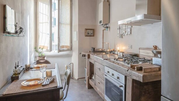 Una cocina con una isla central, estufa y ventana con contraventanas abiertas.