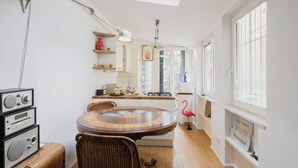A cozy kitchen with a round wooden table, wicker chairs, and a red flamingo decoration. - Easylife - Comfortable studio with terrace Navigli (Milano)