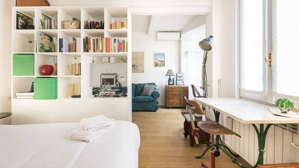 A well-lit room with a bed, a desk with a lamp, a bookshelf, and a window. - Easylife - Comfortable studio with terrace Navigli (Milano)
