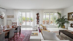 A spacious living room with a dining area, large windows, and a view of the garden. - Easylife - 230sqm attic with terrace Bocconi area (Milano)