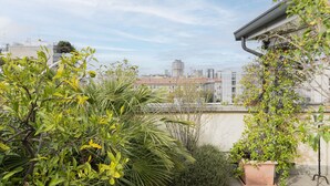 A rooftop garden with various plants and a cityscape in the background. - Easylife - 230sqm attic with terrace Bocconi area (Milano)